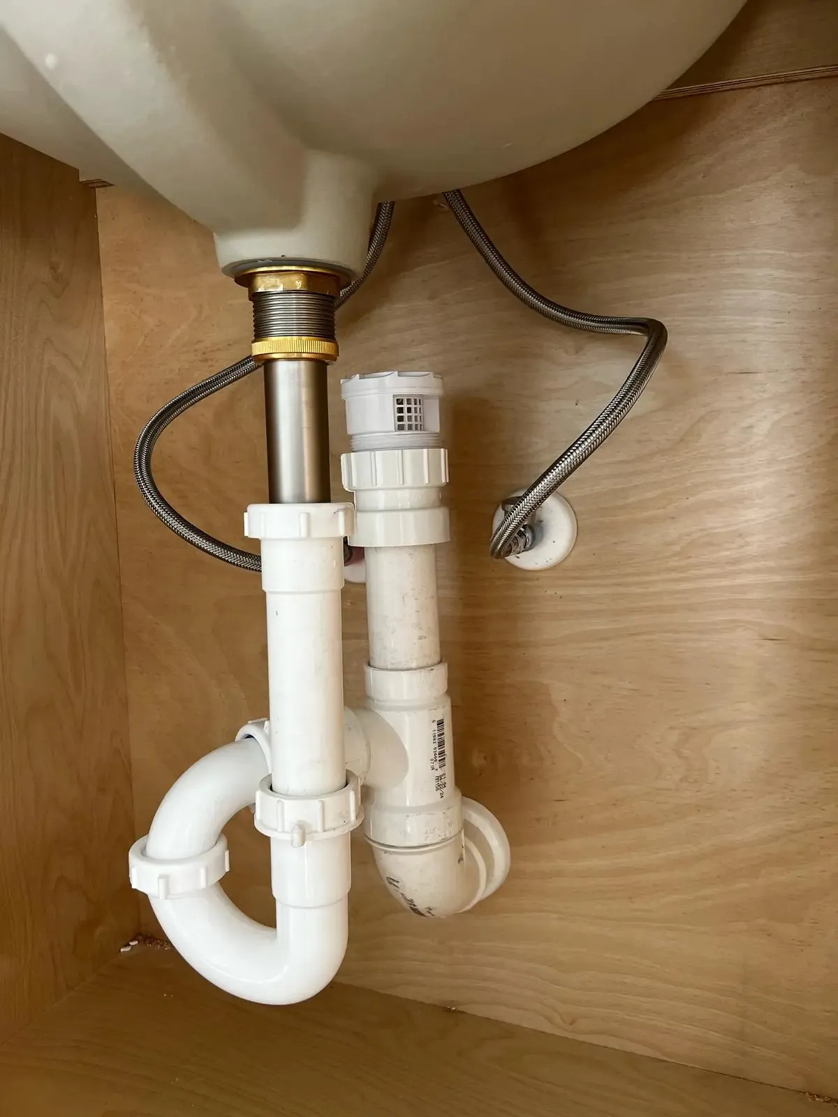 PVC P-trap, drain and braided water supply lines under a bathroom sink