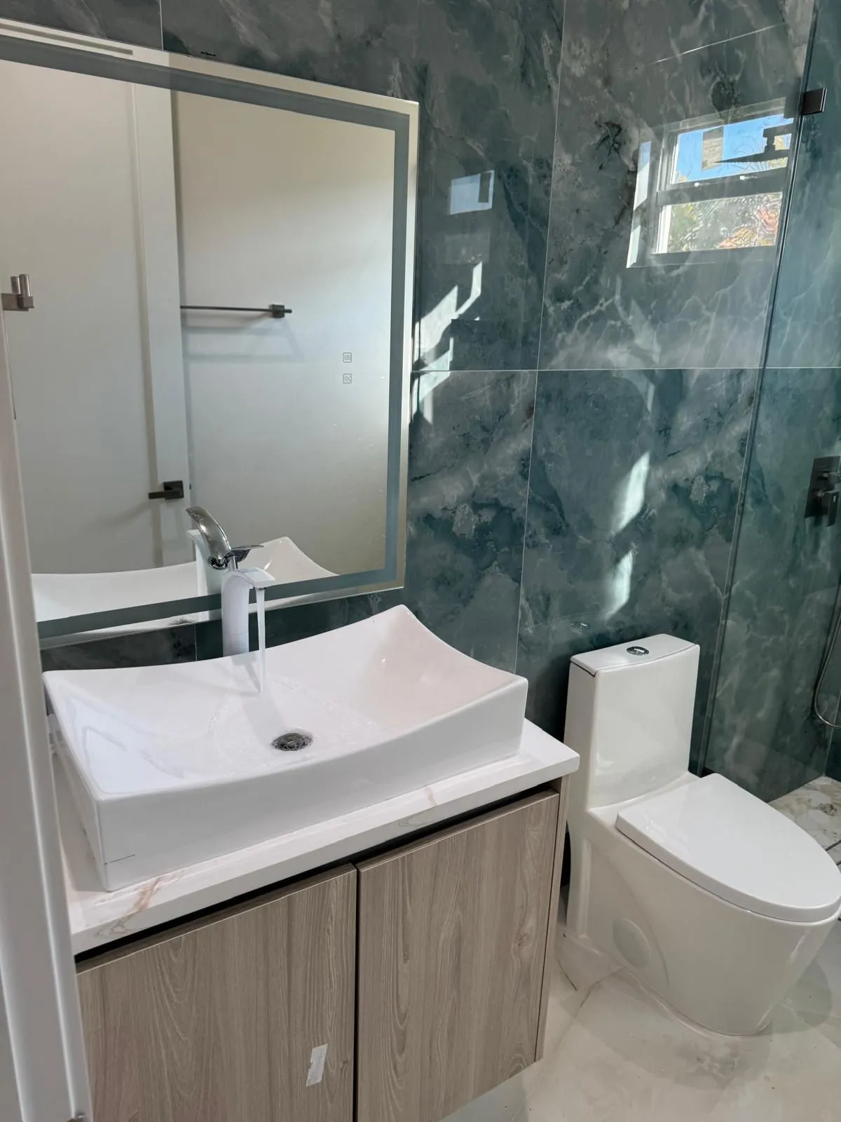 Bathroom with a vessel sink on a floating vanity, tall faucet and one-piece toilet